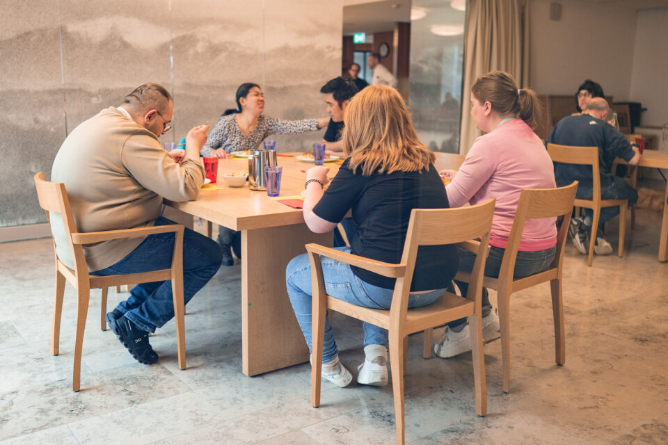 Die Mitarbeitenden des Ateliers essen gemeinsam am Mittagstisch