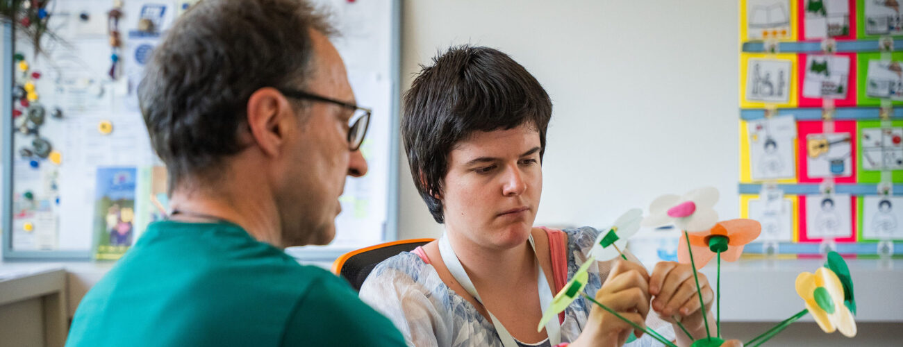 Ein Betreuuer zeigt einer Klientin eine Aufgabe