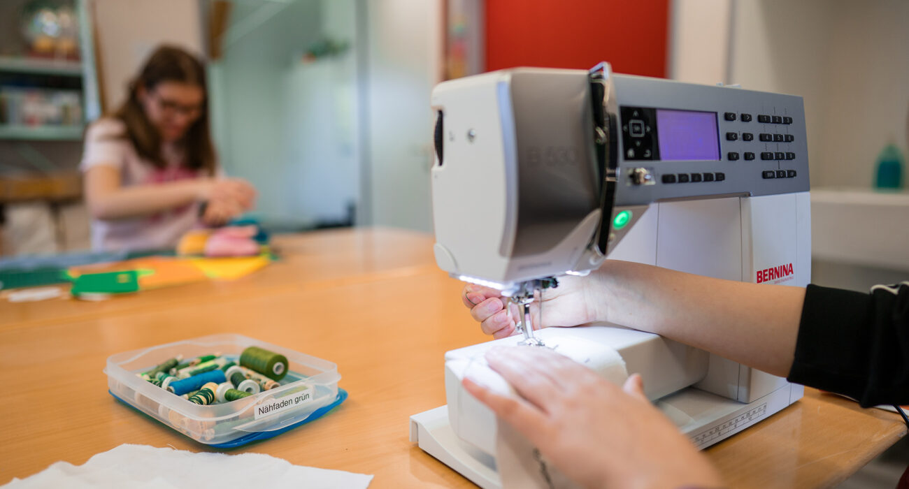 Schülerinnen lernen zu nähen an der Nähmaschine